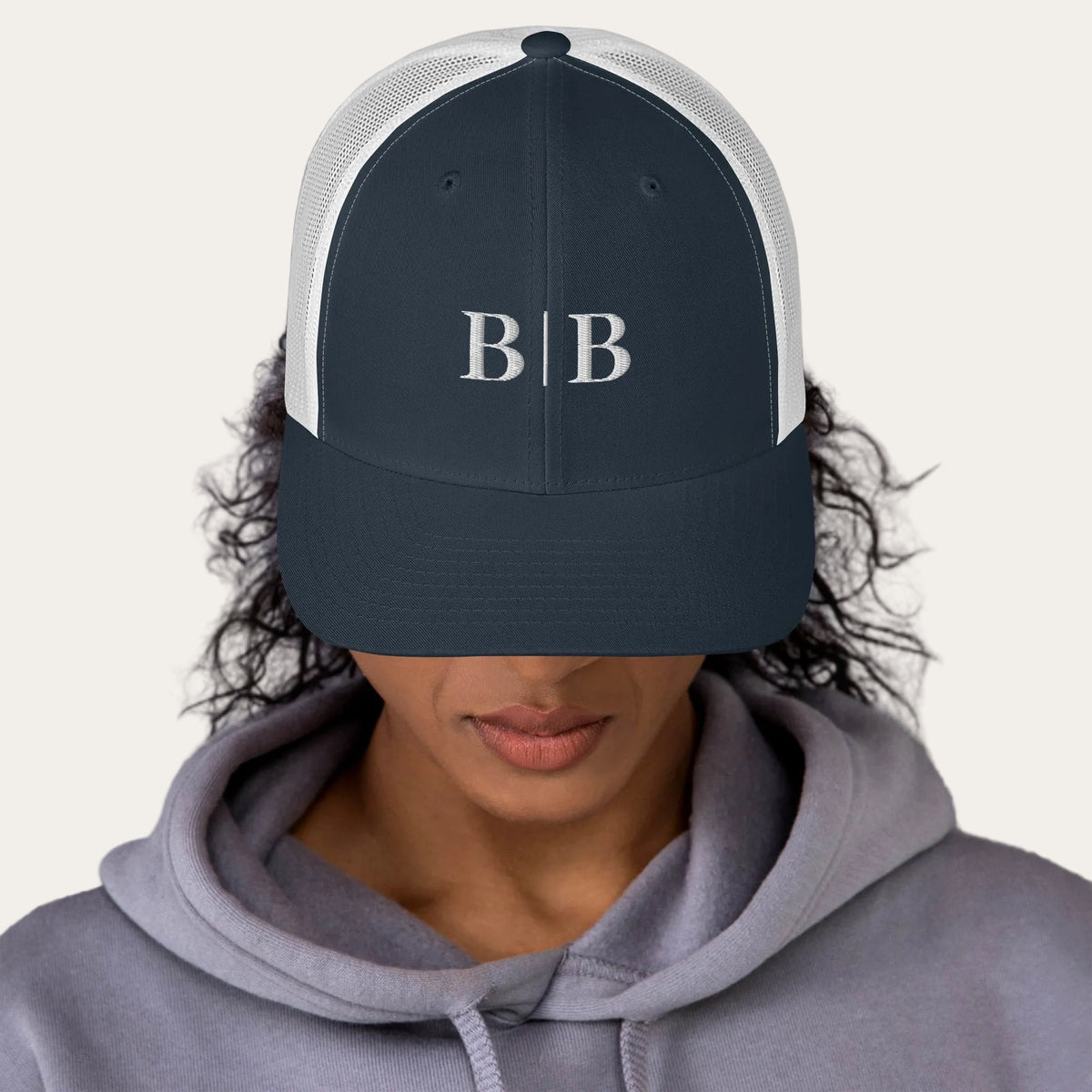Woman wearing the B | B navy trucker hat with a gray hoodie
