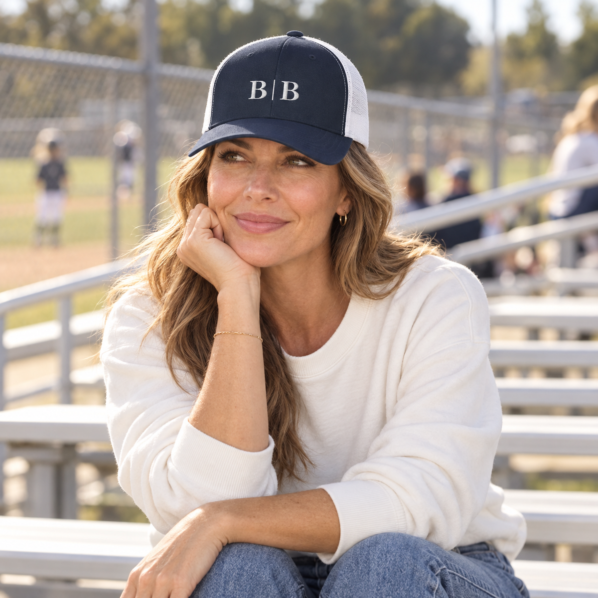 Woman wearing the B | B navy trucker hat at outdoor sports bleachers