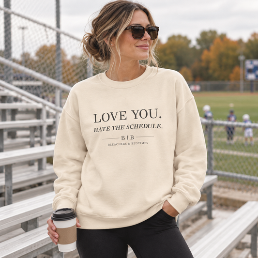 Woman wearing the Love You Hate the Schedule bone crewneck at outdoor bleachers